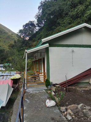 A building with a porch, a staircase leading to a door, and construction materials scattered around.