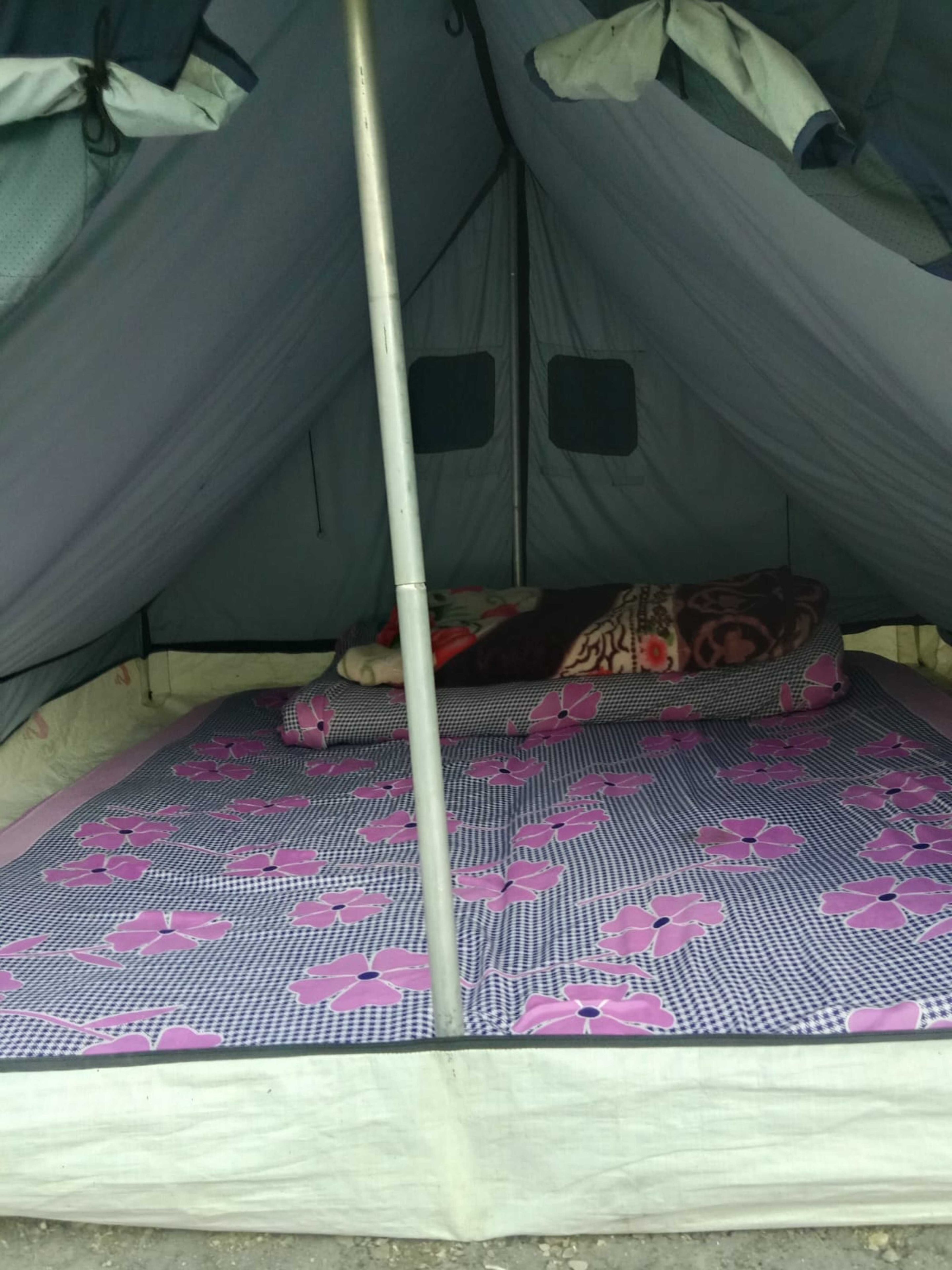 A tent with a single bed featuring a patterned bedspread.