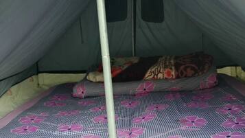 A tent with a single bed featuring a patterned bedspread.