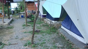 Un campamento con varias tiendas de campaña, un pequeño edificio y un sendero de tierra.