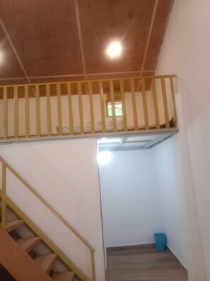 A staircase with a wooden handrail and a yellow railing, leading to a landing with a small window.