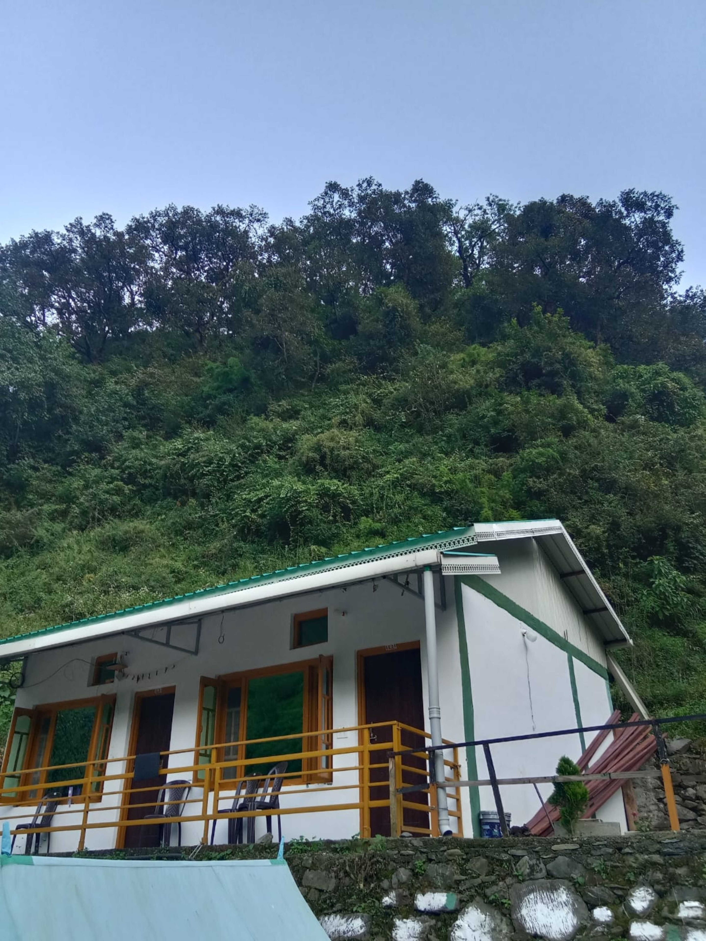A building with a green roof, white walls, and a balcony with yellow railings.