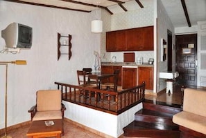 A dining area with a wooden table and chairs, a kitchen in the background, and a staircase leading to another level. - Casas Carmen (San Bartolomé de Tirajana)