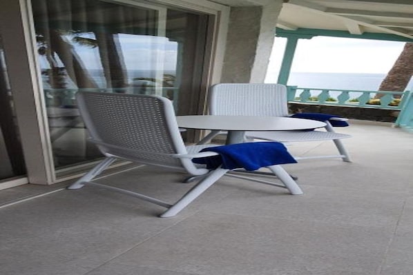 A balcony with a glass door, a white table, and a chair. - Casas Carmen (San Bartolomé de Tirajana)