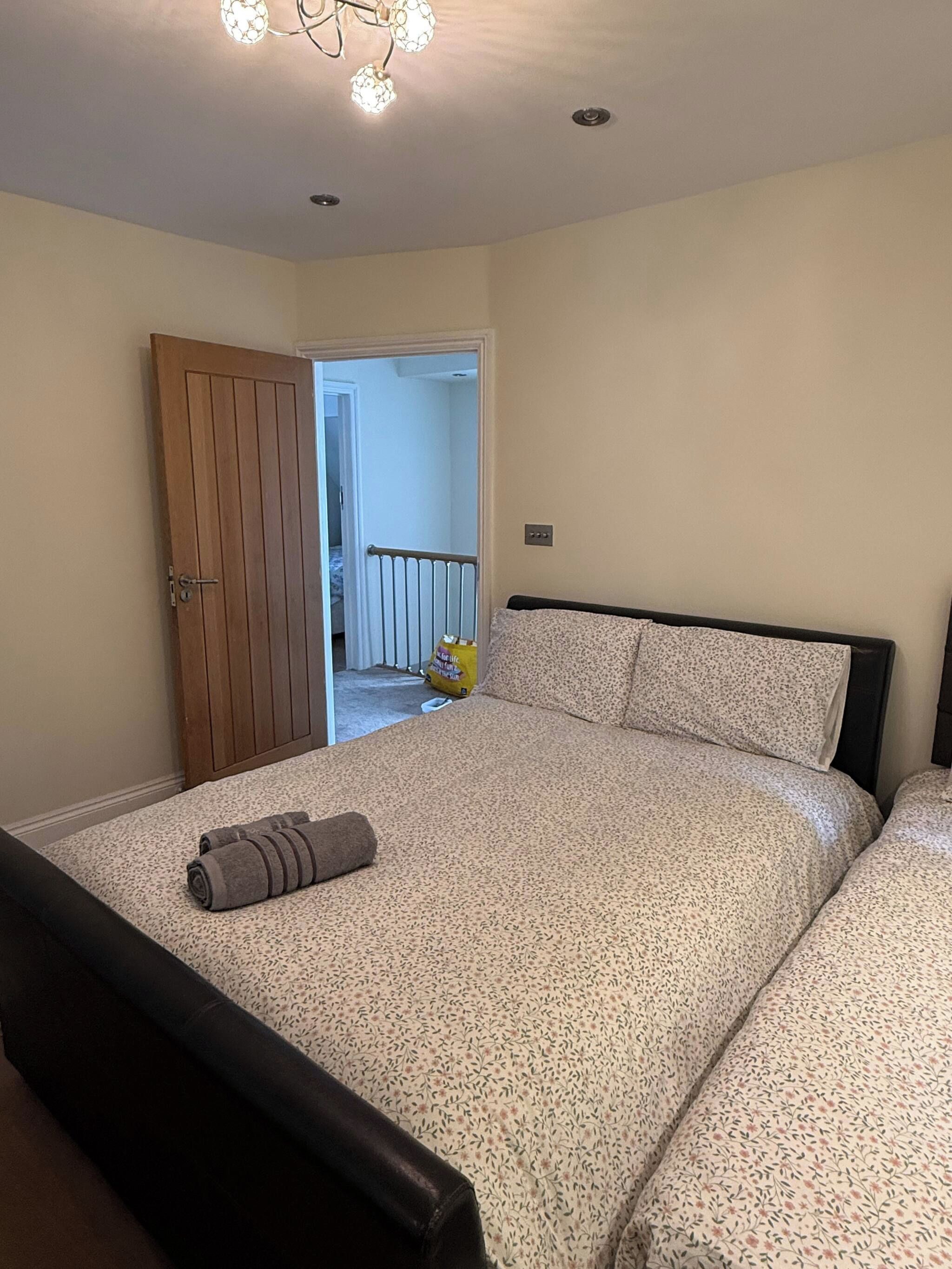 Une chambre à coucher avec un lit, une porte en bois et une vue sur une autre pièce.