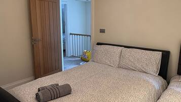 Une chambre à coucher avec un lit, une porte en bois et une vue sur une autre pièce.