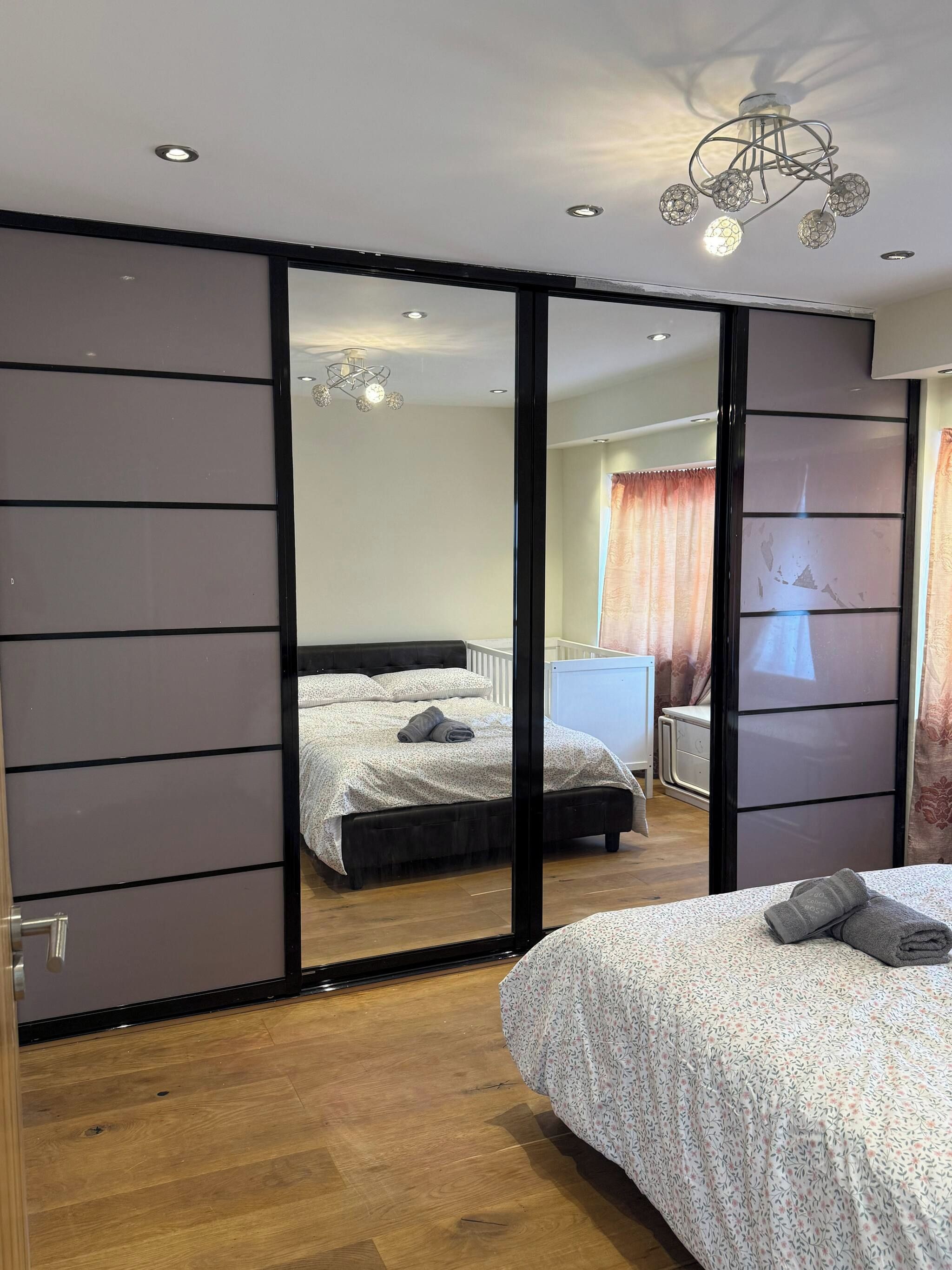 Une chambre à coucher comprenant un lit, une armoire, un miroir et un luminaire au plafond.
