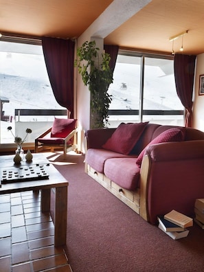 Una habitación acogedora con sofá, sillón, una mesa con un florero y una planta.