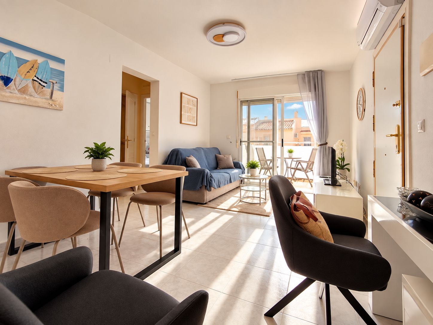 A modern living room with a dining area, a sofa, a TV, and a balcony with a view.