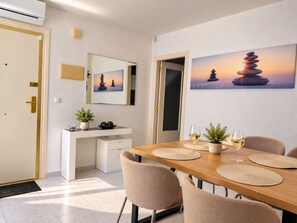 A dining area with a wooden table, beige chairs, and a white console. - Upper-floor bungalow with private solarium and community pool in San Luis (El Chaparral)