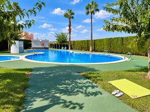 A swimming pool with a surrounding deck, a lifeguard stand, and a small building with a lifebuoy. - Upper-floor bungalow with private solarium and community pool in San Luis (El Chaparral)