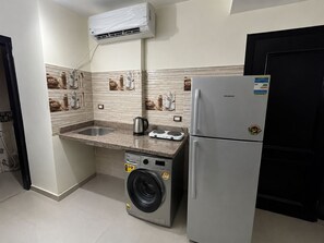 A compact kitchen with a washing machine, a refrigerator, and a sink.