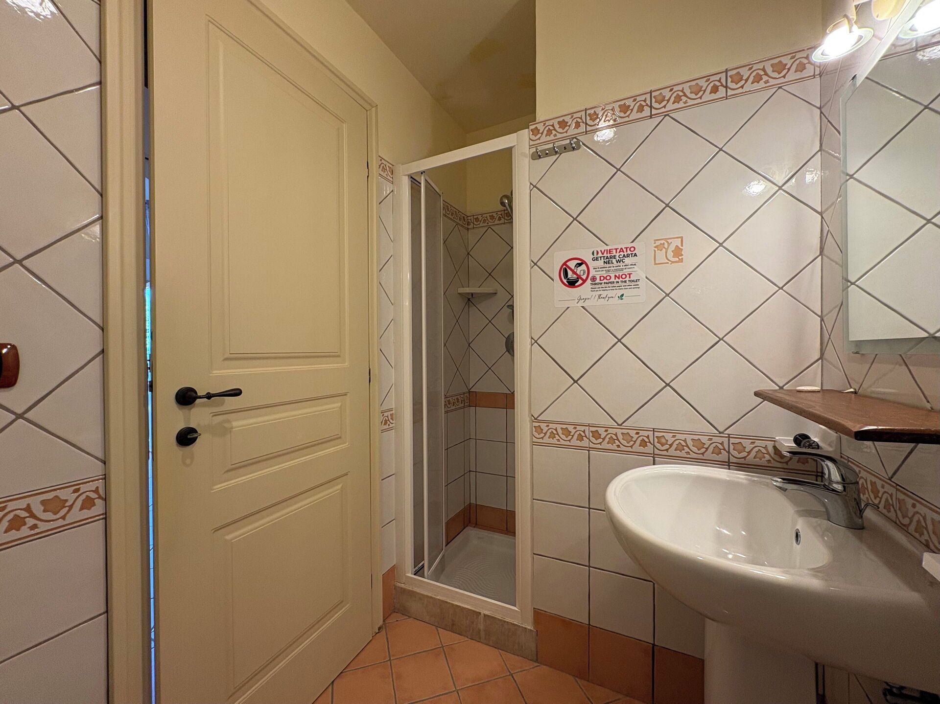 A bathroom with a white sink, a mirror, and a shower stall.