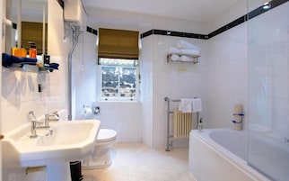 A bathroom with a sink, toilet, bathtub, and a window with a view.