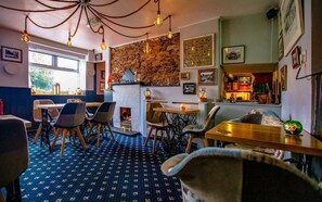 A cozy restaurant with a stone wall, hanging light fixtures, and a patterned carpet. - The Ship In Dock Inn (Dartmouth)