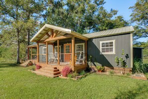 A wooden cabin with a porch, a separate garage, and a well-maintained lawn. - On 80 Acres! Serene Orchard Farm Stay in Lumberton (Lumberton)