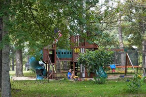 A playground with a slide, climbing structures, and a playhouse. - On 80 Acres! Serene Orchard Farm Stay in Lumberton (Lumberton)