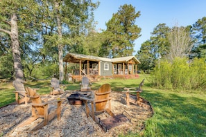 A cabin with a deck, surrounded by trees, and a fire pit with Adirondack chairs. - On 80 Acres! Serene Orchard Farm Stay in Lumberton (Lumberton)