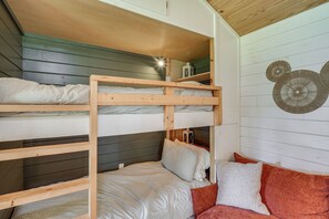 Een slaapkamer met een stapelbed, houten plafond en een decoratief wandobject.