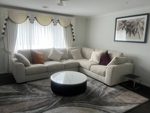 A modern living room with a sectional sofa, a round coffee table, and a framed picture on the wall. - Bonnie brook retreat (Bonnie Brook)