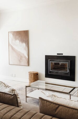A modern living room with a fireplace, a glass coffee table, and a large abstract painting on the wall. - Green Point Town Haus (Cape Town)