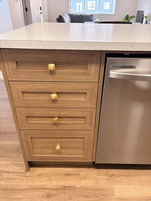 A kitchen with a wooden cabinet and a stainless steel dishwasher. - SpaciousCalgaryHome l 4 Bedrooms l Sleeps 8 plus (Calgary)