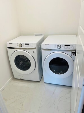 Two Samsung washing machines in a laundry room with a tiled floor. - SpaciousCalgaryHome l 4 Bedrooms l Sleeps 8 plus (Calgary)