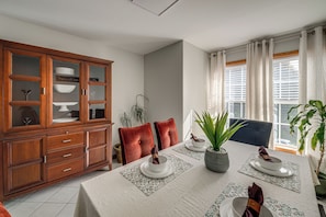 A dining area with a wooden cabinet, a table set with plates, and a window with curtains. - Group Getaway in Paterson, Close to NYC (Paterson)
