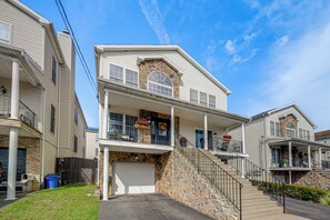 A two-story residential building with a stone facade, a front porch with railings, and a garage. - Group Getaway in Paterson, Close to NYC (Paterson)