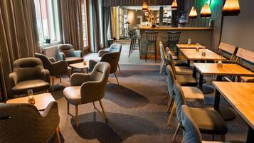 En restaurant med barområde, flere siddepladser inklusive båse og borde, samt et tæppe gulv.
