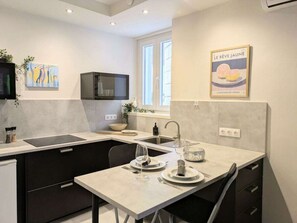 A modern kitchen with a dining area, featuring a built-in oven, a sink, and a window with natural light. - Sibenik Rituals Studio (Sibenik)