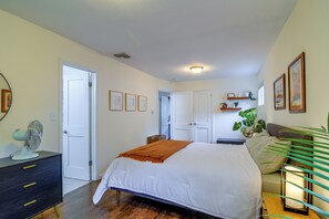 Een slaapkamer met een bed, nachtkastjes, een dressoir, een spiegel en een plafondventilator.
