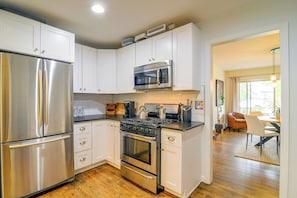 Una cocina moderna con electrodomésticos de acero inoxidable, armarios blancos y suelo de madera.