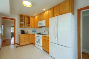 A kitchen with wooden cabinets, a white refrigerator, a stove, and a microwave. - 1 Mi to Beach, Walk to Restaurants Cozy Home (Alameda)