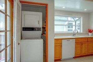 A kitchen with a built-in washer and dryer, wooden cabinets, a window with blinds, and a sink with a faucet. - 1 Mi to Beach, Walk to Restaurants Cozy Home (Alameda)