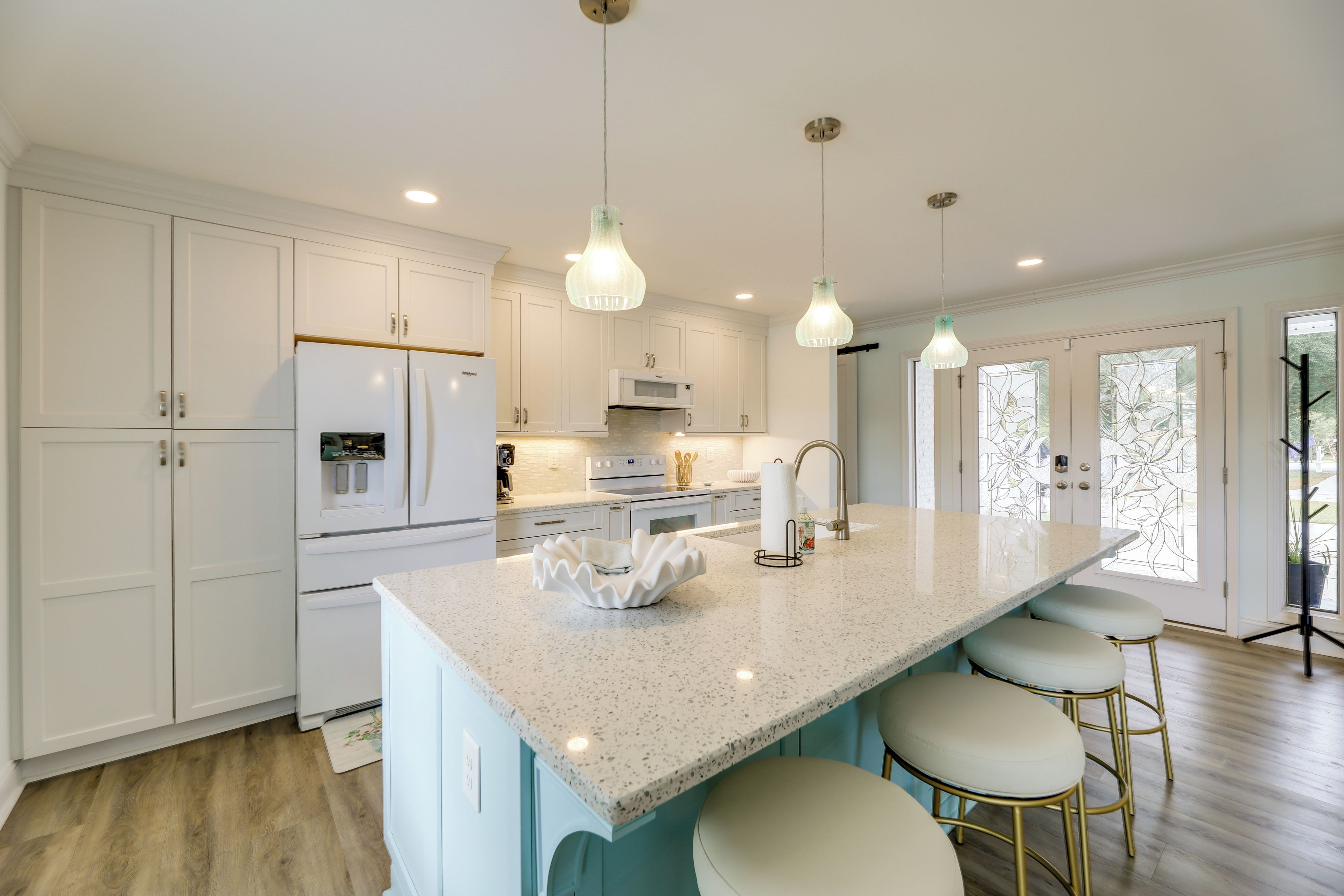 A modern kitchen with white cabinetry, a granite countertop, and pendant lighting.