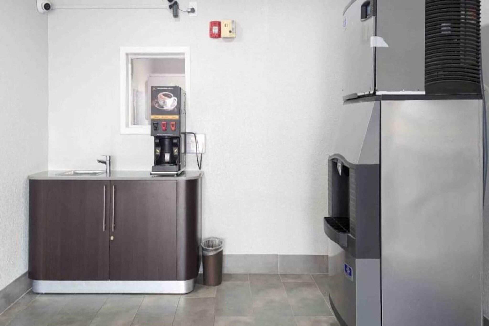 A kitchenette with a coffee machine, a trash bin, and a refrigerator.