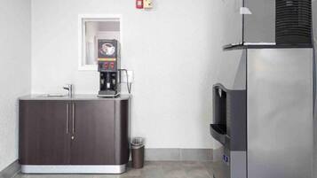 A kitchenette with a coffee machine, a trash bin, and a refrigerator.