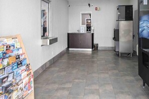 Una cocina con suelo de baldosas, un refrigerador, un microondas y una cafetera.