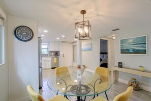 A modern kitchen with white cabinets, a glass dining table, and a clock on the wall. - Pool Access & Lanai! Updated Fort Myers Condo (Fort Myers)