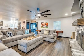 Un salon moderne avec un canapé d’angle, une table basse et un ventilateur de plafond.