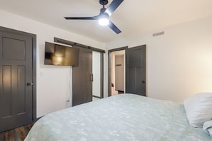 Ein Schlafzimmer mit einem Bett, einem Deckenventilator und zwei Türen.