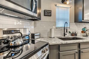 Eine moderne Küche mit Edelstahlgeräten, einem Backofen, einem Wasserkocher, einem Toaster und einem Spülbecken mit Armatur.