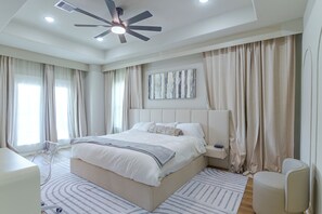 Ein modernes Schlafzimmer mit einem großen Bett, einem Deckenventilator und einem Nachttisch mit Lampe.