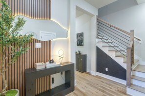 Ein modernes Interieur mit einer Holztreppe, einem Konsolentisch mit Dekoration und einer Topfpflanze.