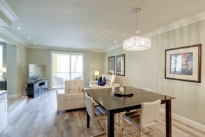 Un espace repas moderne avec une table en bois foncé, des chaises blanches et un lustre.
