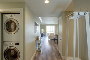 A laundry room with stacked washers and dryers, a hallway leading to a living area with a sofa and a dining table. - Las Vegas Condo Just Off the Strip (Las Vegas)