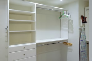 A white wardrobe with multiple shelves and drawers, a hanging rack with clothes, and a towel rack. - Las Vegas Condo Just Off the Strip (Las Vegas)