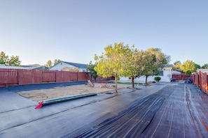 A residential backyard with a paved patio, a wooden fence, and a tree. - 37 Min to Tesla Gigafactory! Sun Valley Home (Sun Valley)