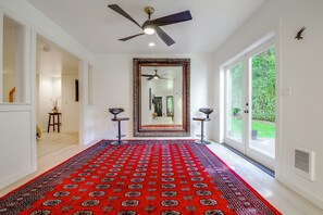 A hallway with a red patterned carpet, a ceiling fan, a large mirror, and two bar stools. - Snohomish Executive Suite w/ Deck & Fire Pit (Snohomish)